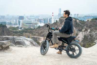 Rider seated on a TXED Maverick electric bike at an outdoor overlook.