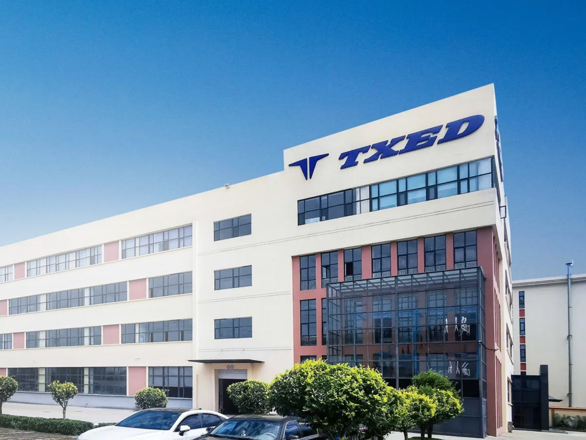 TXED-branded manufacturing building exterior under a blue sky