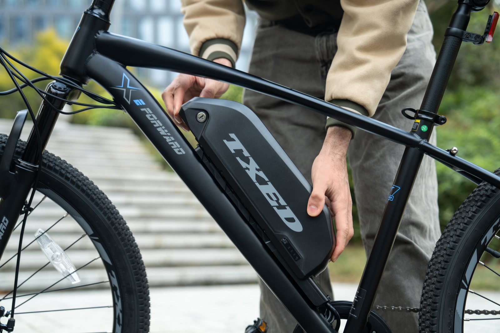 Hands removing the battery from a TXED Trail e-bike